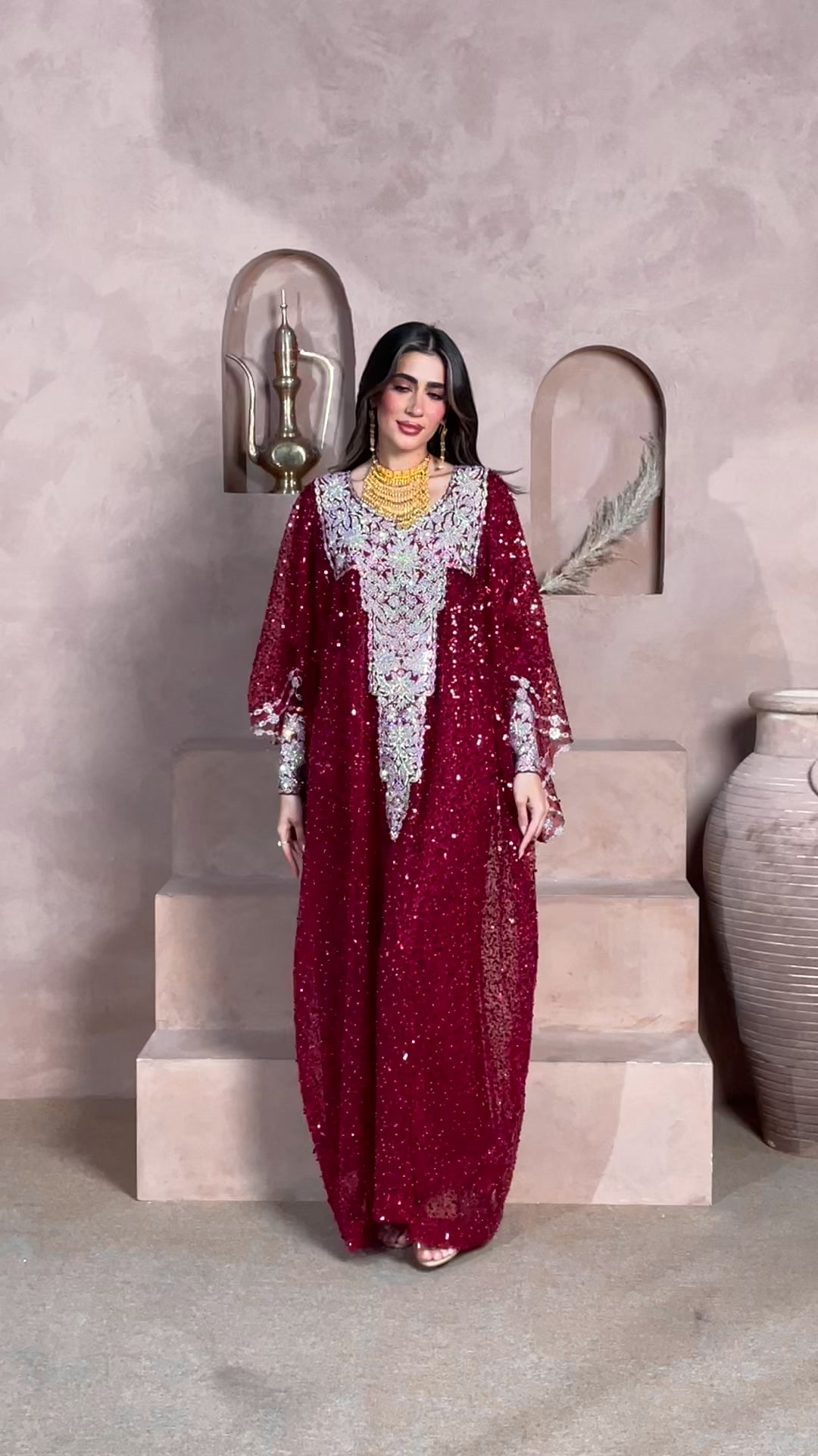 Woman wearing a luxury burgundy sequin kaftan with silver embroidery and gold jewelry, ideal for Eid, weddings, and formal occasions.